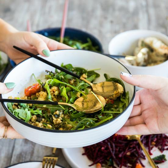 En person rækker en anden person en skål med salat
