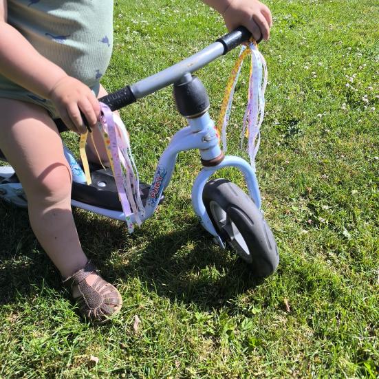 Barn på løbecykel med kvaster på styret