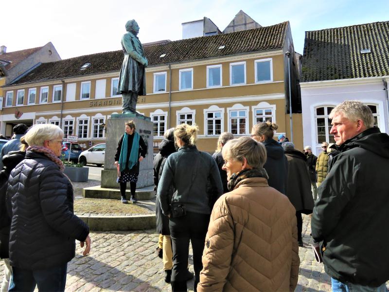 En gruppe mennesker står samlet omkring en skulptur i centrum af Rudkøbing.