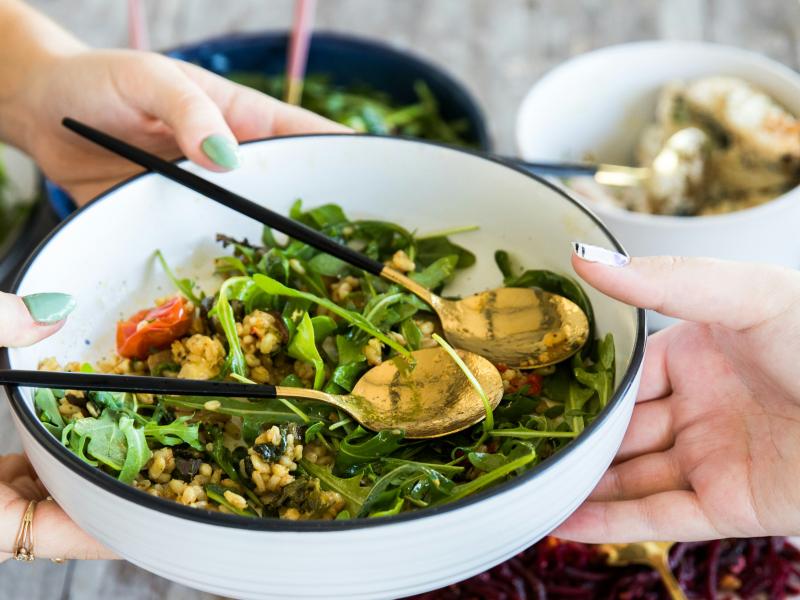 En person rækker en anden person en skål med salat