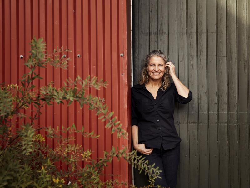 Ane Riel står foran en sort og rød facade og er selv iført sort tøj