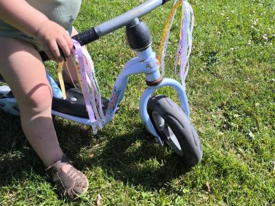 Barn på løbecykel med kvaster på styret