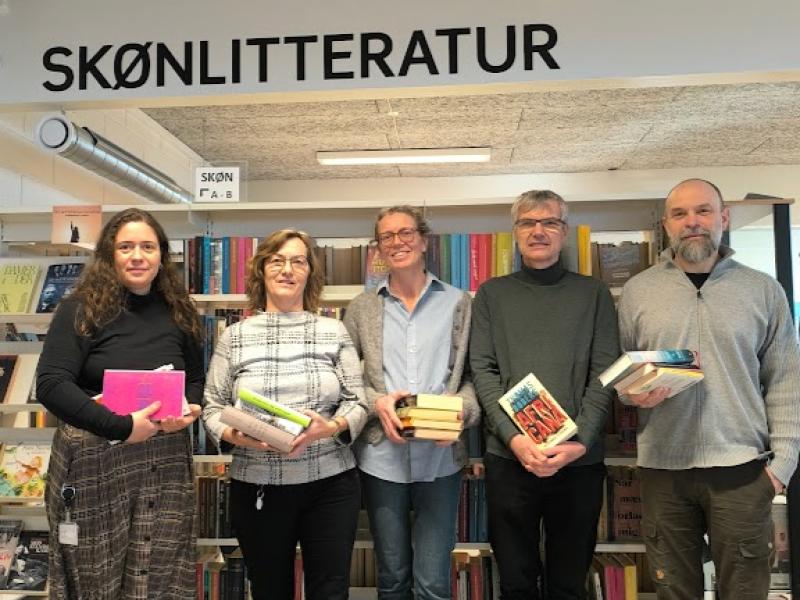 Sofie, Susanne, Maja, Jesper og Kim står hver med en stak bøger foran en bogreol.