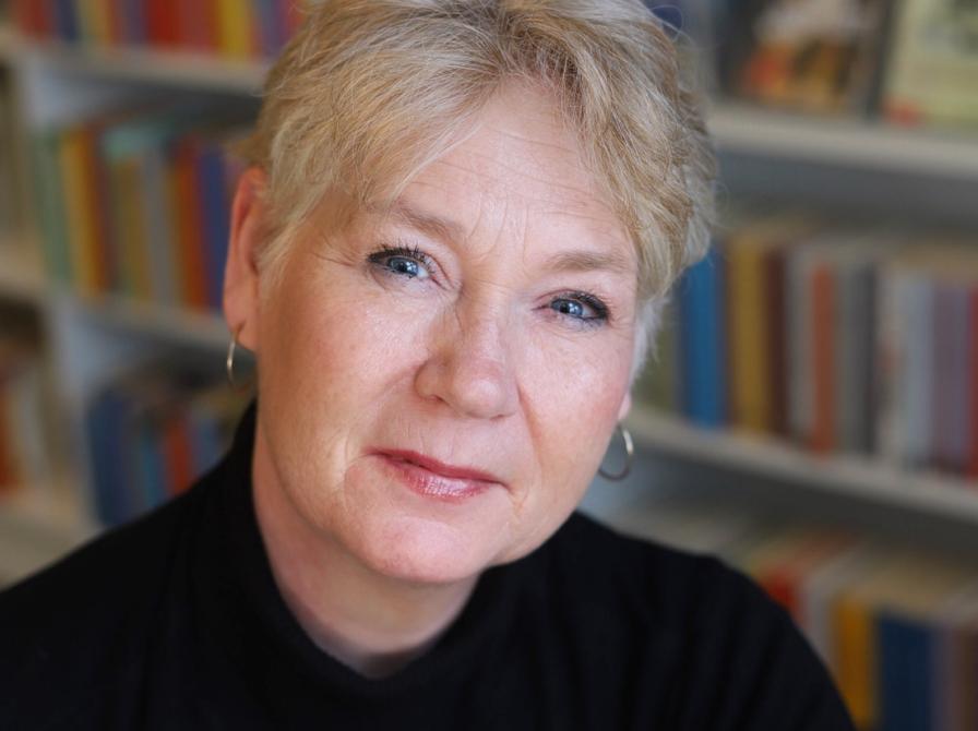 Portrætfoto af Camilla Sejerøe med en bogreol i baggrunden