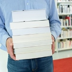 en mand på et bibliotek, der holder en stak bøger