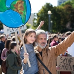 demonstration for klimaet med en mand og et barn i forgrunden