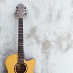 en akustisk guitar står lænet op ad væggen