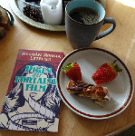Bogen "Pigen der fortalte film", en kop kaffe og kage og jordbær