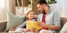 en far læser, snakker og griner med sin datter