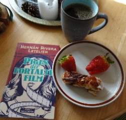 en bog, en kop kaffe og en tallerken med kage og jordbÃ¦r
