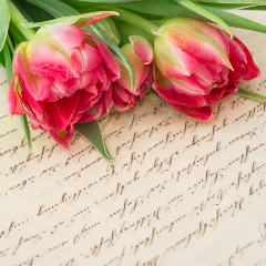 et gammelt håndskrevet brev med en buket roser ovenpå