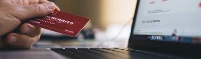 En hånd med et kreditkort parat til at betale på internettet