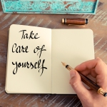 en hånd der skriver i en notesbog: take care of yourself